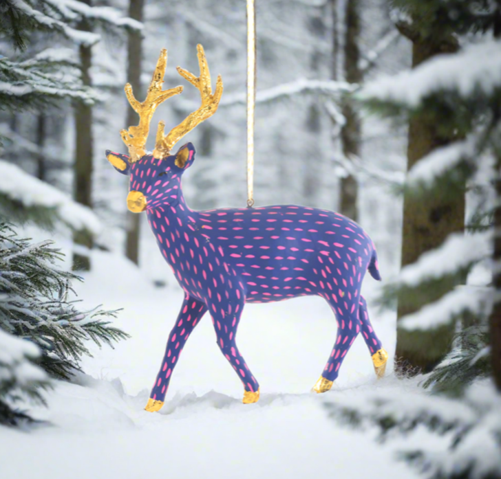 The Canton Christmas Shop Blue and Pink Paper Deer Ornament in the snowy woods at Christmas