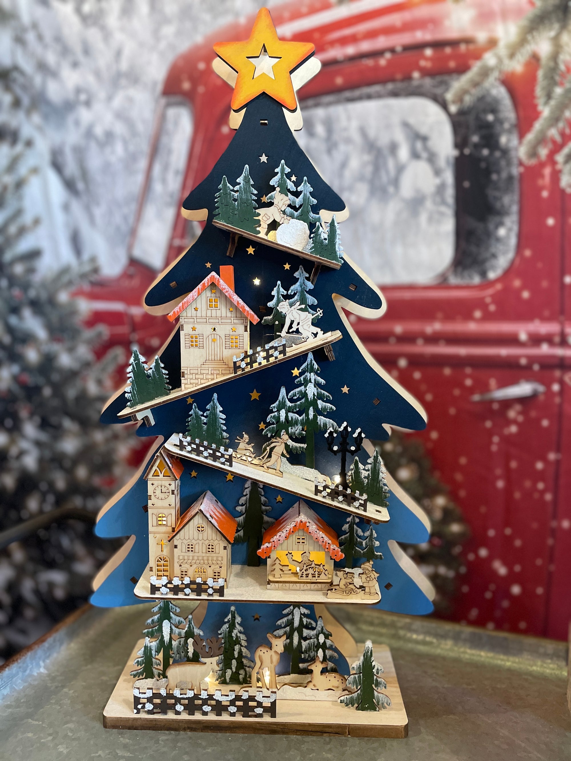 The Canton Christmas Shop Battery-Operated Light-Up LED Blue Wooden Christmas Tree with Village Scene Carved Animals Nature Wildlife Skiing Sledding Church in Shop