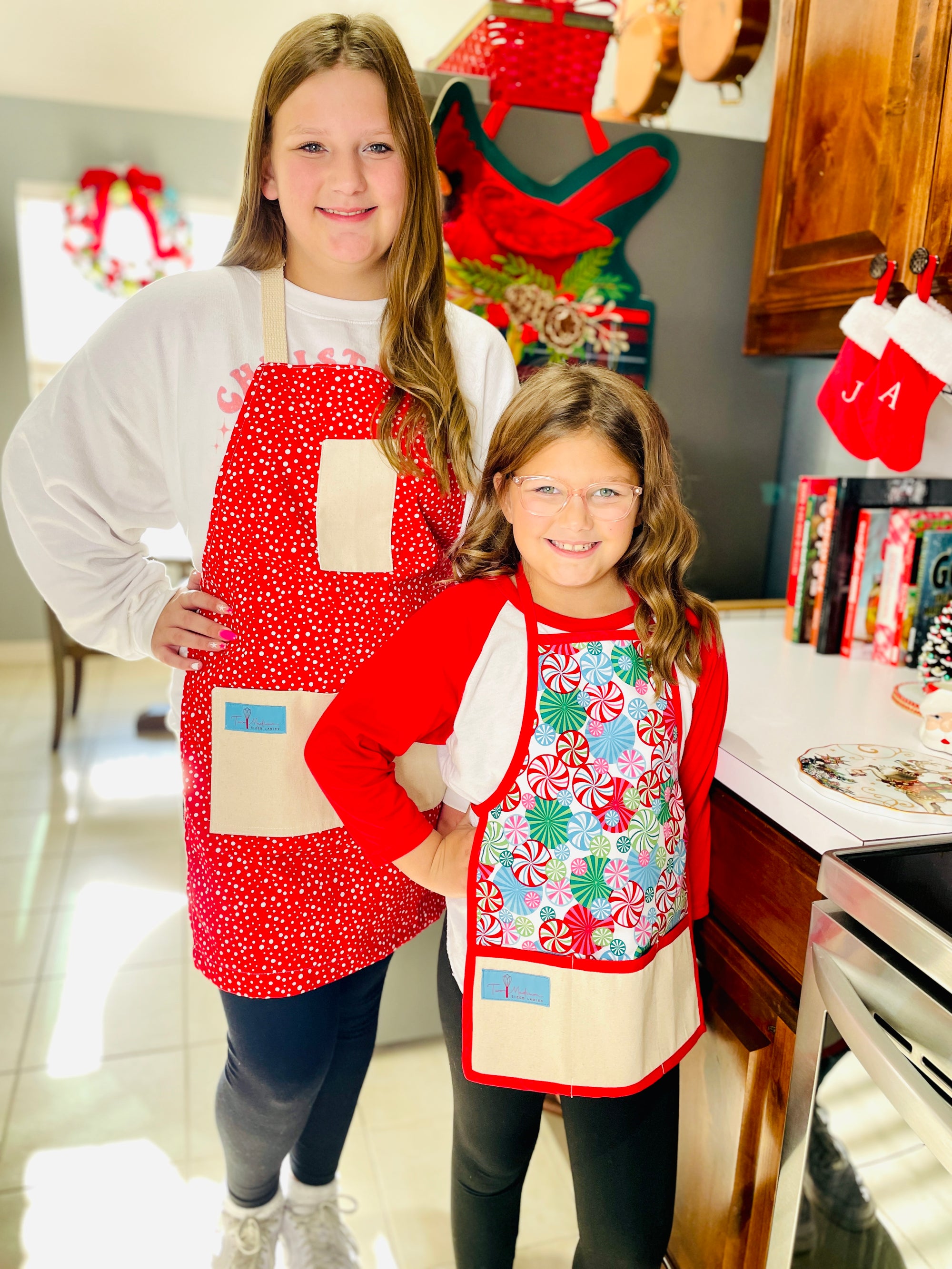 The Canton Christmas Shop Vintage Snowfall Apron and children's Peppermint Lane apron by Two Medium Sized Ladies handmade in Texas